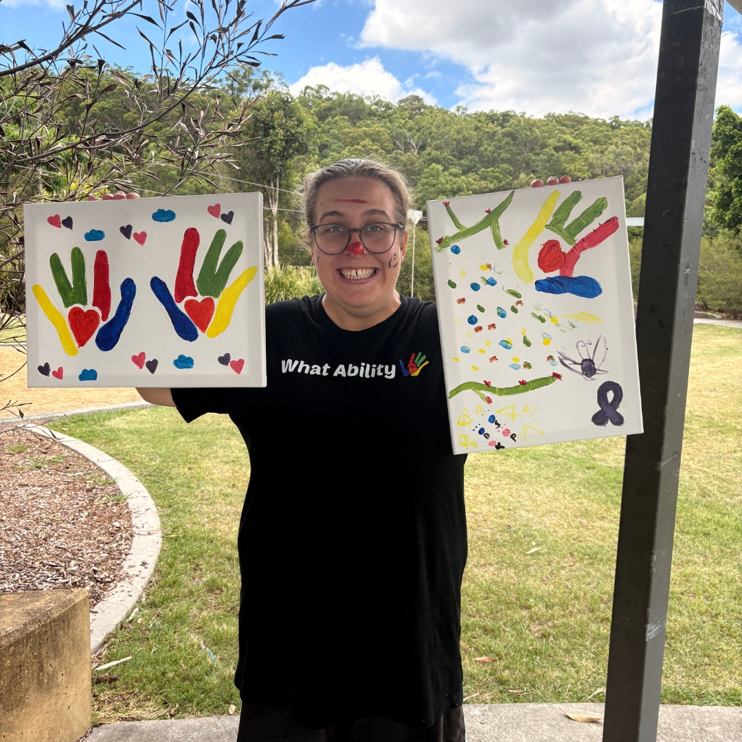 Participant holding painted canvas of the What Ability logo